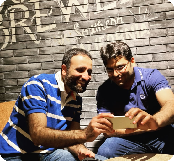 Two colleagues smiling while looking at a smartphone